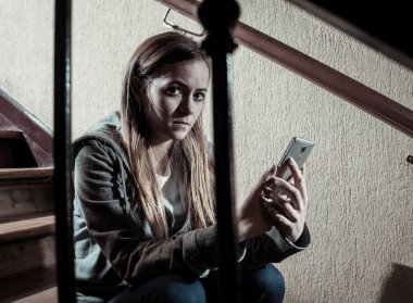 Siber zorbalık istismarı muzdarip online Stalker genç kız kurbanı yalnız ve umutsuz koyu ışık merdivenlerde oturan duygu. İnternet tehlikeleri, çevrimiçi bakım ve taciz konsepti.