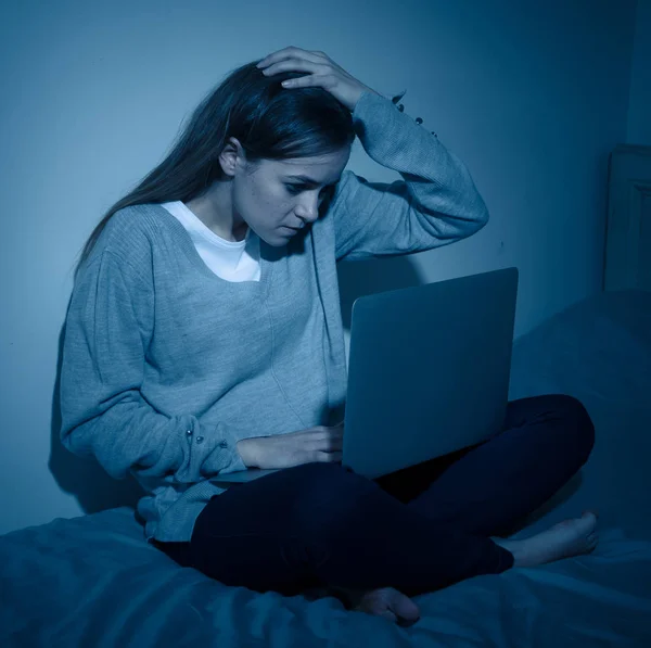 Scared and intimidated sad teenager bullied on line with laptop suffering cyberbullying and harassment. Child victim of bullying stalker social media, online challenges and dangers of internet.