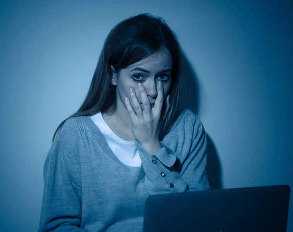 Scared and intimidated sad teenager bullied on line with laptop suffering cyberbullying and harassment. Child victim of bullying stalker social media, online challenges and dangers of internet.