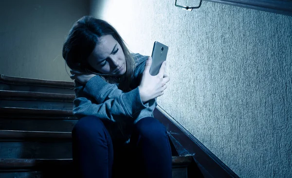 悲しい落ち込んだ若い十代の若者たちの少女は 階段上のモバイルスマートフォンの立地によるネットいじめの被害孤独 絶望的で虐待を感じています ソーシャルメディアアプリ上のテキストメッセージによっていじめ ダークライト — ストック写真