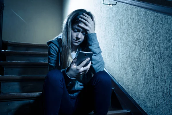 十代の女の子がネットいじめに苦しむオンラインストーカーの被害者暗い光と階段に座って孤独と絶望的な感じ インターネットの危険性 オンライングルーミングとハラスメントの概念 — ストック写真