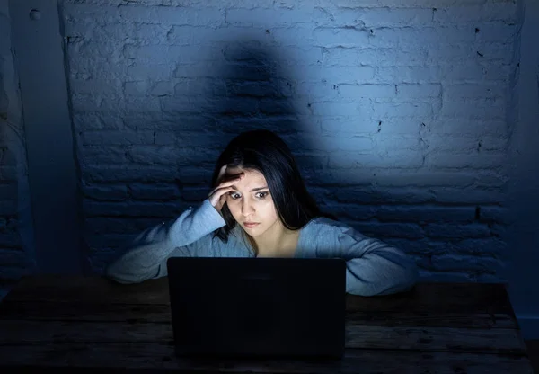 Dramatic portrait of sad scared young woman stressed and worried in front of laptop suffering cyber bullying and harassment. Being online abused by stalker. In Internet problem concept.