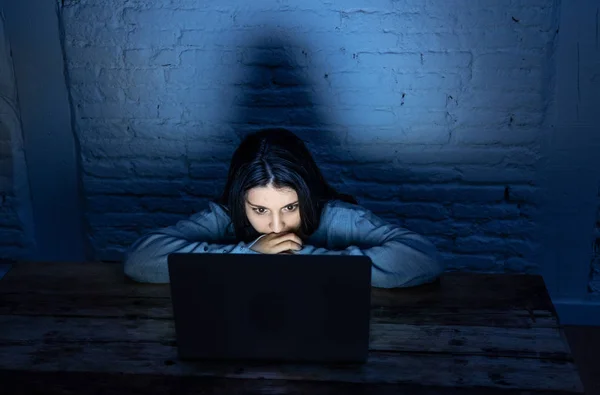 Dramatic portrait of sad, scared young woman on laptop suffering cyber bullying and harassment. Being online abused by stalker feeling desperate, humiliated and intimidated in dangers of Internet.