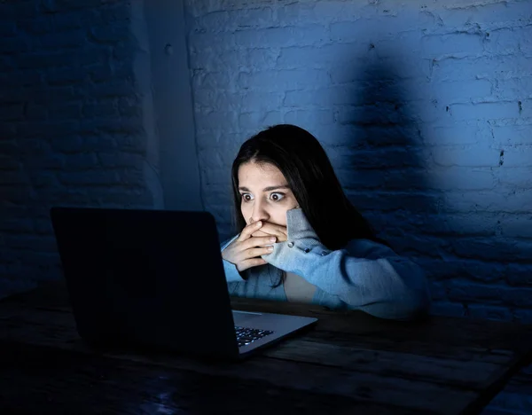 Dramatic portrait of sad and scared young woman with laptop suffering cyber bullying and harassment. Being online abused by stalker feeling desperate and humiliated in Internet problem concept.