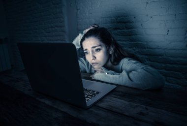Dramatic portrait of sad scared young woman stressed and worried staring at laptop suffering cyber bullying and harassment. Victim of online abuse and intimidation by stalker. In dangers of internet. clipart