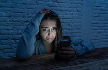 Üzücü korkmuş genç kadın çevrimiçi taciz ve siber zorbalık kurbanı dramatik portresi. akıllı cep telefonu bakarak vurguladı ve korku online Stalker tarafından istismar olmak. İnternet tehlikeleri.