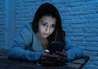 Siber zorbalık ve taciz acı akıllı cep telefonu üzücü korkmuş genç kadının dramatik portresi. Yalnız, depresif ve korku online Stalker tarafından istismar olma hissi. İnternet tehlikeleri.