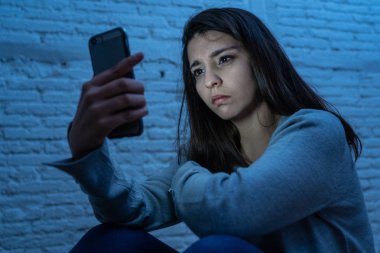 Gece katta üzgün korkmuş genç kadın portre vurguladı ve akıllı cep telefonu tehdit siber zorbalık taciz muzdarip. Stalker tarafından istismar online olmak umutsuz ve depresif.