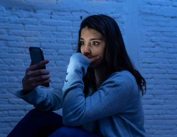 Gece katta üzgün korkmuş genç kadın portre vurguladı ve akıllı cep telefonu tehdit siber zorbalık taciz muzdarip. Stalker tarafından istismar online olmak umutsuz ve depresif.