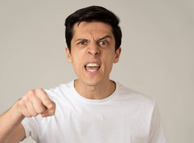 Kızgın bir yüzü olan genç beyaz erkek yakın. Deli ve çılgın bağırarak ve öfkeli jestler yapıyor. Beyaz arka planda izole edilmiştir. Yüz ifadeleri ve duygular.