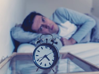 Uykusuz ve çaresiz genç beyaz adam Uykusuz geceleri uyku mümkün değil, hayal kırıklığına ve stres ve uyku bozukluğu kavramı uykusuzluk muzdarip saat bakıyor endişeli.
