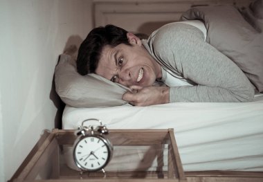 Uykusuz ve umutsuz genç adam uykusunda uyku mümkün değil, sinirli duygu ve uykusuzluk acı saat sıkıntı bakarak endişeli. Zihinsel sağlık, stres ve uyku bozukluğu.