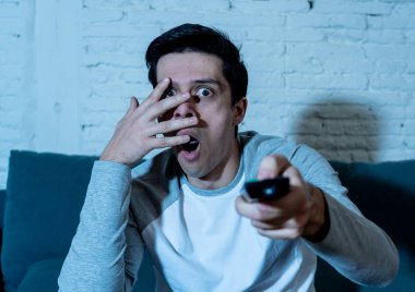 TV 'de korku filmi veya hoş olmayan şiddet sahnesini izlerken genç korkmuş adamın yaşam tarzı portresi. Geceleri evde korku ve şok. Kitle iletişim alanında şiddet, eğlence ve morbid gösterileri.