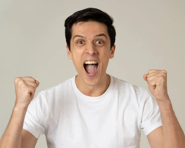 Portrait of young shocked man winning the lottery or having great success with surprised and happy face and gestures. In People, Facial Expression, Human Emotions and celebration. Studio shot.