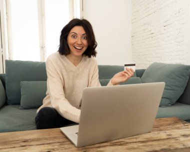Evde dizüstü bilgisayar ve kredi kartı alışveriş online oturan mutlu genç kadın
