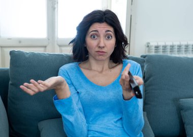 Genç üzgün kadın kanepede kontrol uzaktan zapping kullanarak kötü Tv şovları ve programlama sıkılmış . İlgisiz, ilgisiz ve uykusuz görünüyor. İnsanlar, çok fazla kötü televizyon ve Sedanter yaşam tarzı.