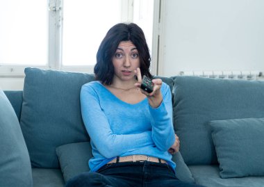 Genç üzgün kadın kanepede kontrol uzaktan zapping kullanarak kötü Tv şovları ve programlama sıkılmış . İlgisiz, ilgisiz ve uykusuz görünüyor. İnsanlar, çok fazla kötü televizyon ve Sedanter yaşam tarzı.