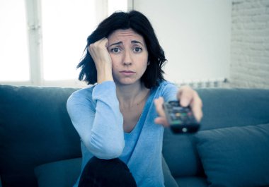 Genç üzgün kadın kanepede kontrol uzaktan zapping kullanarak kötü Tv şovları ve programlama sıkılmış . İlgisiz, ilgisiz ve uykusuz görünüyor. İnsanlar, çok fazla kötü televizyon ve Sedanter yaşam tarzı.