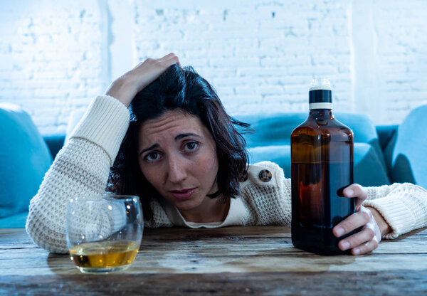 Drunk alcoholic depressed woman drinking scotch whiskey spirits alone at home. Feeling hopeless, week and lonely. In People lifestyle, Depression, alcohol addiction, alcoholism and drug abuse concept.