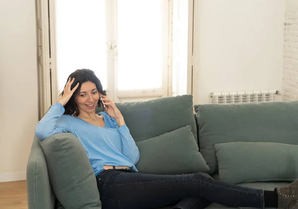 Giovane donna felice che parla con lo smartphone seduta sul divano di casa. Nel tempo libero e nella tecnologia — Foto Stock