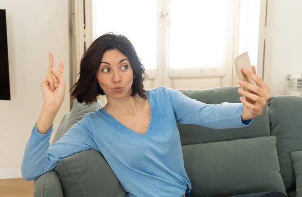 Joyeux jeune femme Prendre un selfie sur téléphone portable assis sur le canapé à la maison — Photo