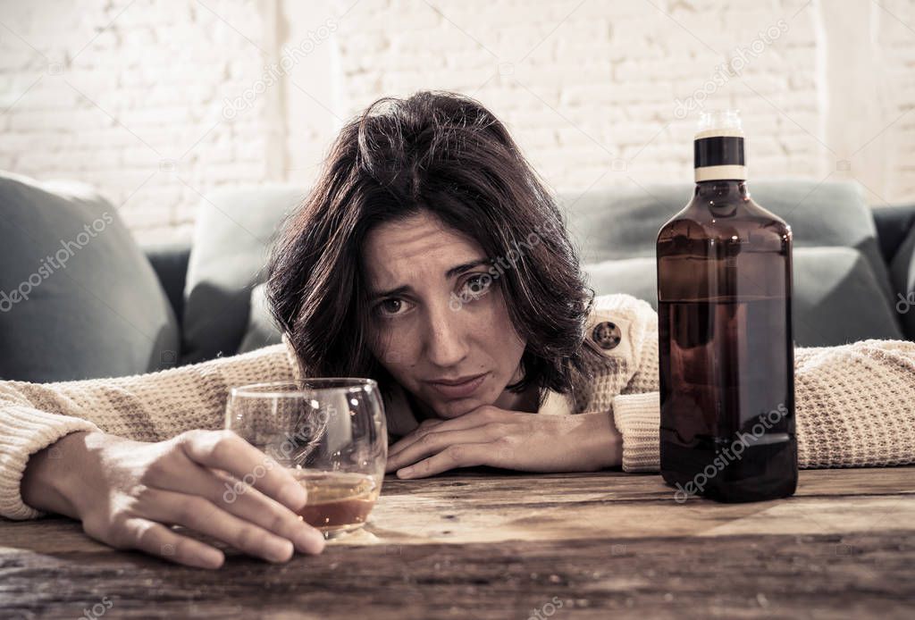 Drunk alcoholic depressed woman drinking scotch whiskey spirits alone at home. Feeling hopeless, week and lonely. In People lifestyle, Depression, alcohol addiction, alcoholism and drug abuse concept.