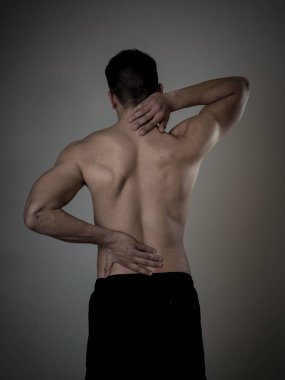 Genç Kas Fitness adam dokunmadan ve boyun ve alt sırt acı servikal ağrı nötr arka planda izole kapma. Spor ve egzersiz yaralanması, yanlış duruş sorunları ve vücut bakımı.