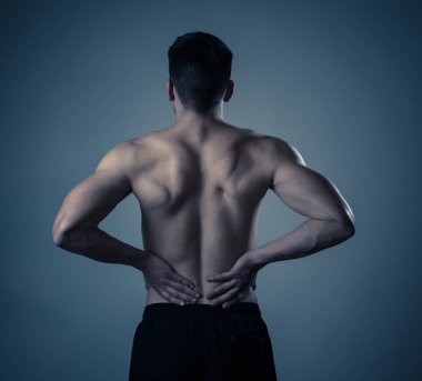 Genç Kas Fitness adam dokunmadan ve egzersiz sonrası güçlü ağrı acı onun alt sırt kapma. Nötr arka planda izole. Spor yaralanması yanlış duruş sorunları ve vücut sağlık bakımı.