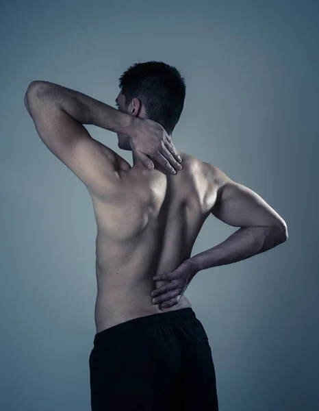 若い筋肉のフィットネスの男は 彼の首と腰の苦しみ中立の背景に隔離された子宮頸部の痛みに触れ つかむ スポーツやトレーニングの怪我では 不適切な姿勢の問題とボディケア — ストック写真
