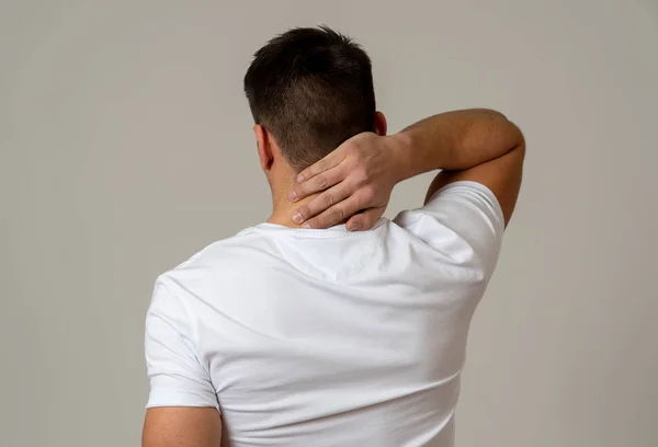 若い筋肉のフィットネスの男は 彼の首と上の背中をつかむと 中立の背景に隔離された子宮頸部の痛みに苦しんでいます スポーツ傷害不適切な姿勢の問題と体の健康管理 — ストック写真