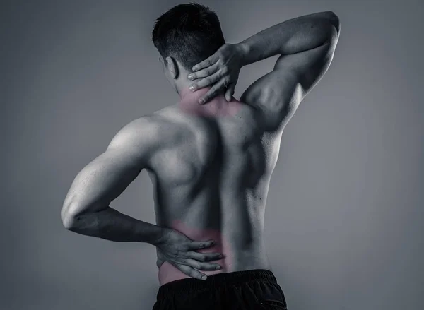 Young muscular fitness man touching and grabbing his neck and lower back suffering cervical pain isolated on neutral background. In sport and workout injury, Incorrect posture problems and body care. — Stock Image Young Muscular Fitness Man Touching Grabbing His Neck Lower Back Stock Image