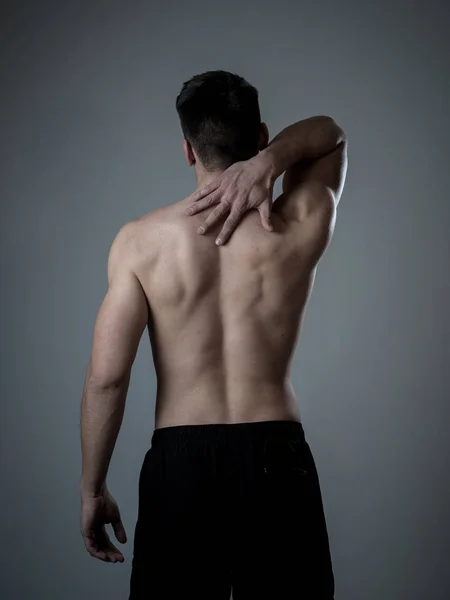若い筋肉フィットの男は トレーニング後に子宮頸部の痛みに苦しんで首と上背部をつかんでつかみます ニュートラルな背景で隔離されています スポーツ傷害不適切な姿勢の問題と体の健康管理 — ストック写真