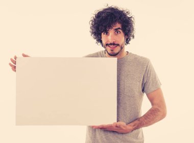 Komik ve iyi görünümlü milenyal adam gösteren ve metin için kopya alanı ile boş tahta işaret. Samimi ve heyecanlı genç şık adam reklam için boş poster tutuyor. Pazarlama konsepti.