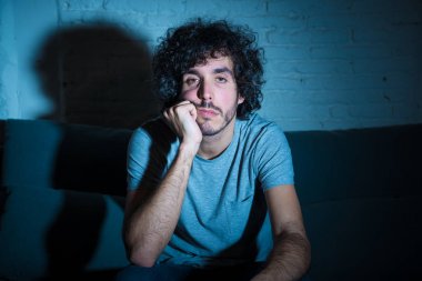 Başka bir film veya gece geç saatlerde göstermek için TV uzaktan kumanda zap kullanarak kanepede genç sıkılmış adam. İlgilenmiyor ve uykusuz görünüyorsun. Eğlence Insanlar uykusuzluk ve sedanter yaşam tarzı kavramı.
