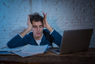 Aşırı çalıştı ve stresli genç öğrenci laptop duygu sıkıntılı yorgun endişeli ve üzücü yoruldu gece geç saatlere kadar sınava hazırlanıyor. Moody koyu ışık. Online öğrenme, üniversite eğitimi ve stres.