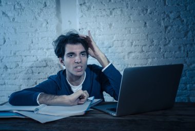 Aşırı çalıştı ve stresli genç öğrenci laptop duygu sıkıntılı yorgun endişeli ve üzücü yoruldu gece geç saatlere kadar sınava hazırlanıyor. Moody koyu ışık. Online öğrenme, üniversite eğitimi ve stres.