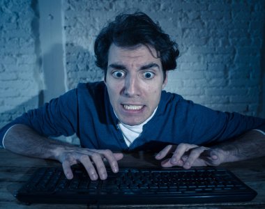 Bilgisayar laptop hissi geceleri yalnız bağımlısı genç adam vurguladı ve iş bitirmek veya online oyun veya kumar kazanmak için çalışırken boğulmuş. İşkolik ve internet teknolojisi bağımlılığı.