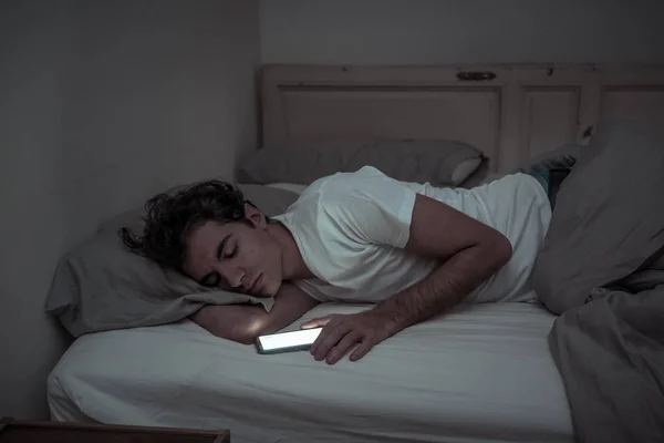 침대에서 스마트 전화와 미디어 남자에 모바일 조명에 어두운 침실에서 남자의 — 스톡 사진