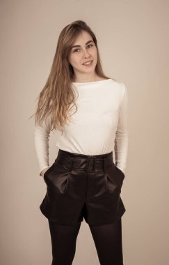 Uzun sarışın saçlı ve güzel gülümsemesi ile genç güzel genç kadın yarı uzunlukta stüdyo portre. Kendine güvenen, rahat ve güzel poz ve modelleme Feeling. Insanlar yaşam tarzı ve gençlik güzelliği.