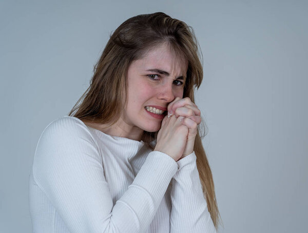 Close up portrait of young teen woman feeling afraid and shocked hiding her face from something scary. Looking with fear in her eyes. People and Human expressions and emotions concept. Studio shot.