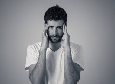 Büyük acı içinde migren muzdarip endişeli ve düşünceli görünümlü genç bir adamın yakın portresi. Nötr arka planda izole edilmiş. Yüz ifadeleri ve duygular ve sağlık bakım kavramı.