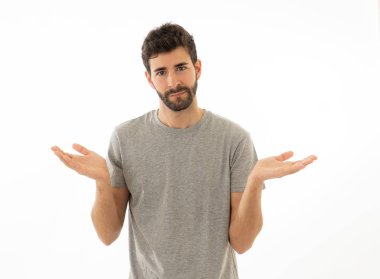 Çekici genç adam portresi hiçbir fikrim yok yüzünde belirsizlik ve habersiz ve sorgulanan bir görünüm ile el ele tutuşarak habersiz jest yapıyor. Beyaz arka planda izole edilmiş. İnsan ifadesi.