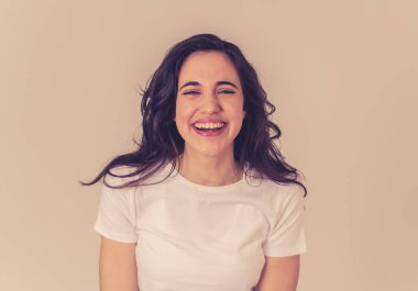 Mutlu yüz güzel gülümseme ve uzun siyah saçlı çekici esmer genç latin kadının yakın portresi. Nötr arka planda izole edilmiş. İnsanlar, pozitif insan yüz ifadesi ve duygu.