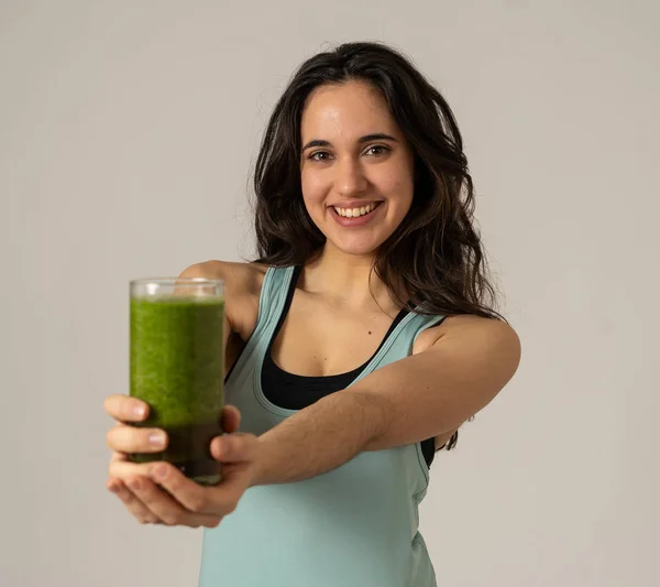 Fitness woman happy smiling holding glass of green vegetable smoothie after running or workout. Portrait isolated with copy space. Beauty Health Fitness Diet Nutrition and healthy Lifestyle concept.