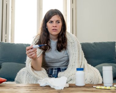 Sağlık ve tıp. Evde kanepede yatan hasta kadın baş ağrısı burun ağrısı ile hasta burun termometre hissi ile yüksek sıcaklık kontrol yorgunluk ve huzursuz işe gitmek mümkün değil.