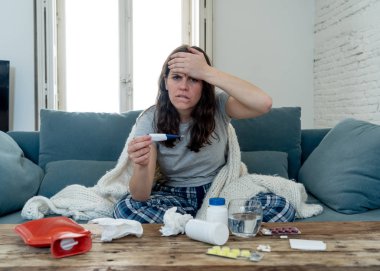 Sağlık ve tıp. Evde kanepede yatan hasta kadın baş ağrısı burun ağrısı ile hasta burun termometre hissi ile yüksek sıcaklık kontrol yorgunluk ve huzursuz işe gitmek mümkün değil.