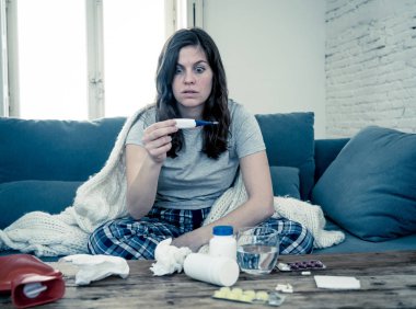 Sağlık ve tıp. Evde kanepede yatan hasta kadın baş ağrısı burun ağrısı ile hasta burun termometre hissi ile yüksek sıcaklık kontrol yorgunluk ve huzursuz işe gitmek mümkün değil.