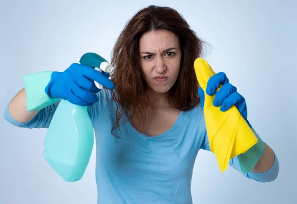 Angry and upset woman with cleaning spray and cloth cleaning feeling frustrated. The stain will not come out. In domestic duties and cleaning products advertising image isolated on blue background.