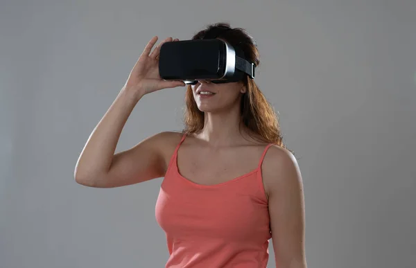 Curious woman happy and excited to use virtual reality goggles feeling excited about simulation, exploring virtual life making happy gestures. In New technology Virtual Augmented Reality concept.