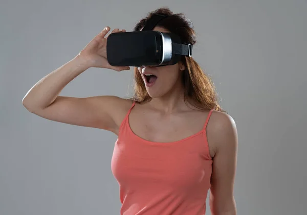 Curious woman happy and excited to use virtual reality goggles feeling excited about simulation, exploring virtual life making happy gestures. In New technology Virtual Augmented Reality concept.